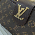 Close-up of a brown leather bag with gold logo on a white background
