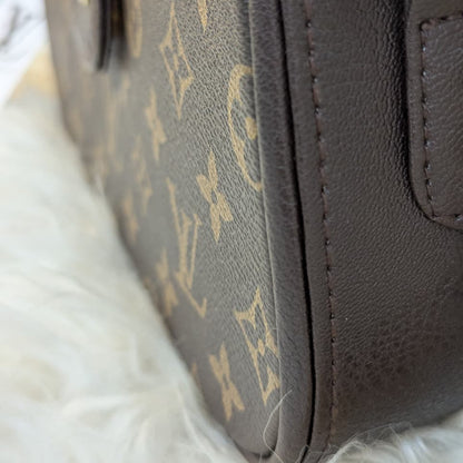 Close-up of a brown leather handbag with a visible brand logo on a white fur surface.